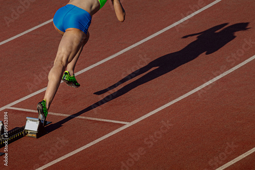 start female athlete from starting blocks running sprint distance, shadow woman runner on stadium track