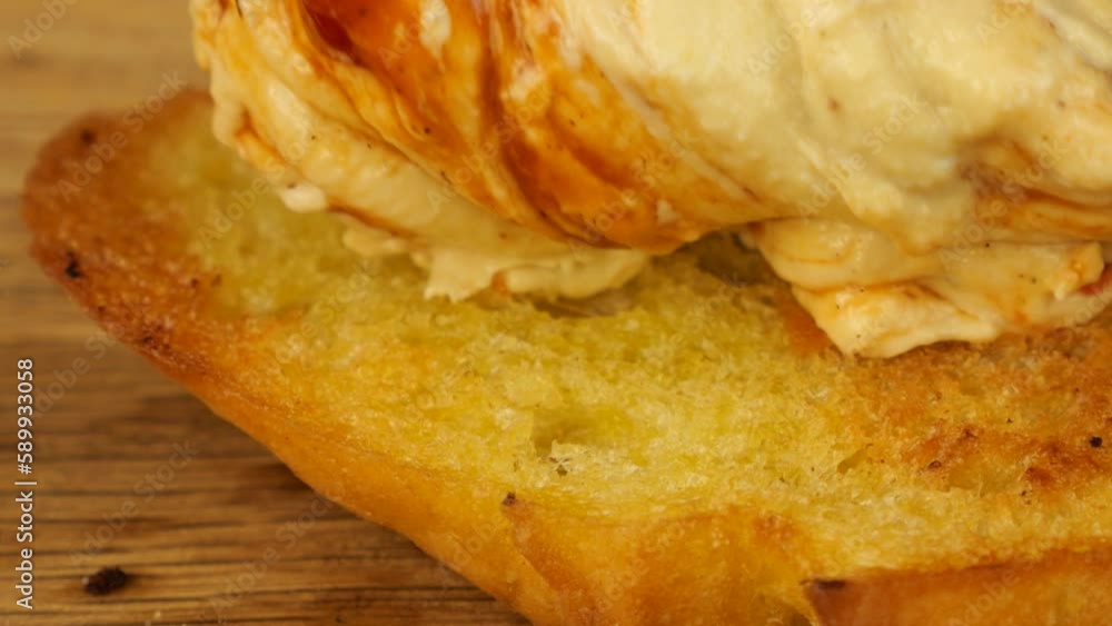 Hummus is spread with a knife on a piece of toasted bread against a background of assorted appetizers. Food for vegans. Hummus is spread with a knife on a piece of toasted bread against a background of assorted appetizers. Food for vegans.