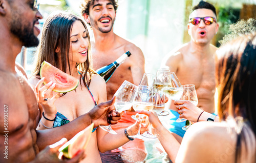 Trendy friends group drinking white wine champagne at private pool side party - Life style vacation concept with young men and women having fun together on summer day at luxury resort - Bright filter © Mirko Vitali