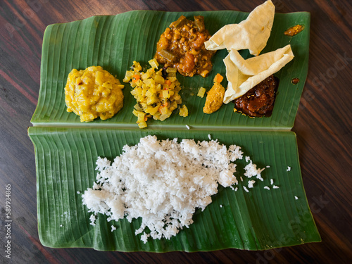 South Indian cuisine banana leaf rice serve with various curry and vegetable. photo