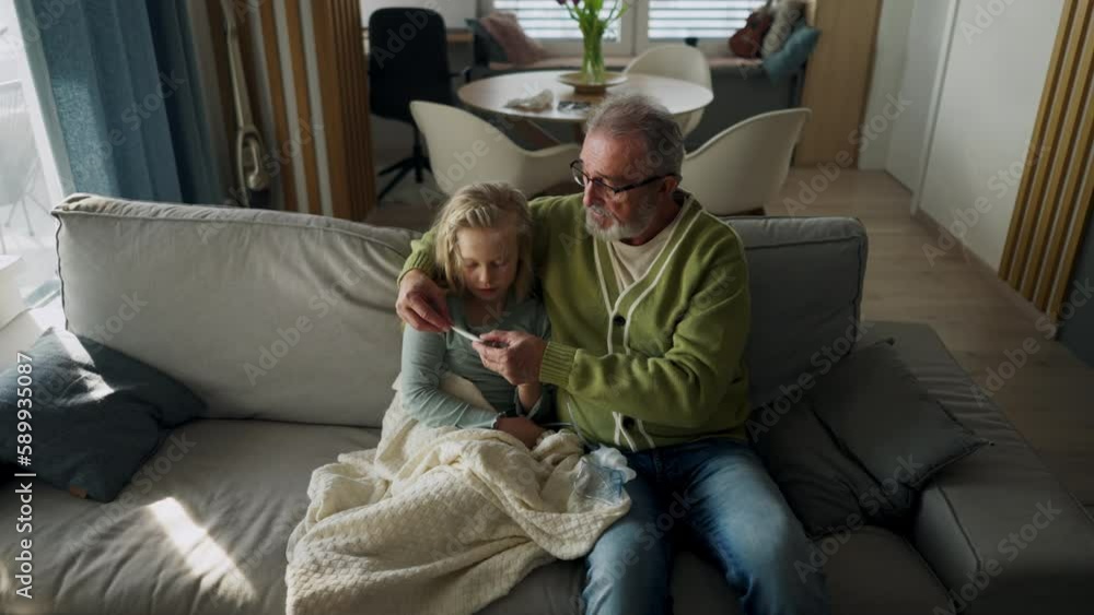 Senior man taking care of sick granddaughter, measuring her temperature. Senior man taking care of sick granddaughter, measuring her temperature.