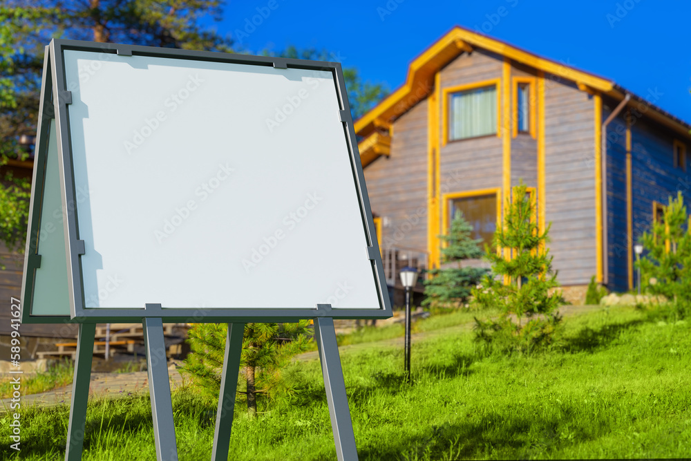 Signboard near house. Two-storey cottage with empty banner. Portable billboard. Signboard for house sale message. Blank advertising sign on lawn of cottage. Template, mock up. Art blurred. 3d image