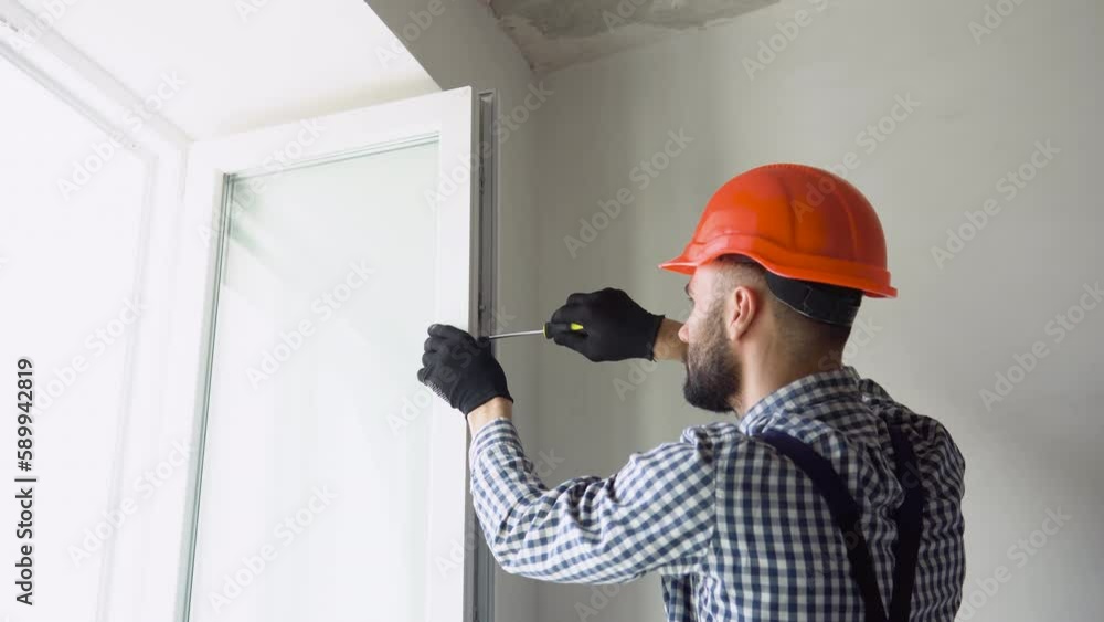 Worker installs and adjusts a new plastic window in house. Repairman regulates Installation and adjustment Worker installs and adjusts a new plastic window in house. Repairman regulates Installation and adjustment