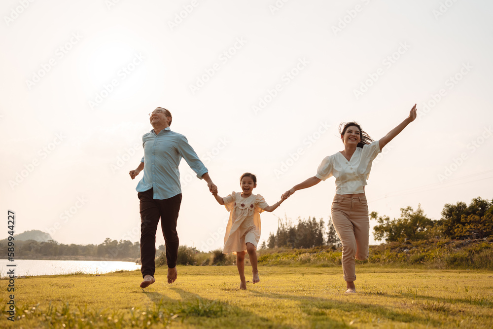 Happy Family enjoying a peaceful walk and running in a scenic field with a serene lake in the background. Happy Family enjoying a peaceful walk and running in a scenic field with a serene lake in the background.