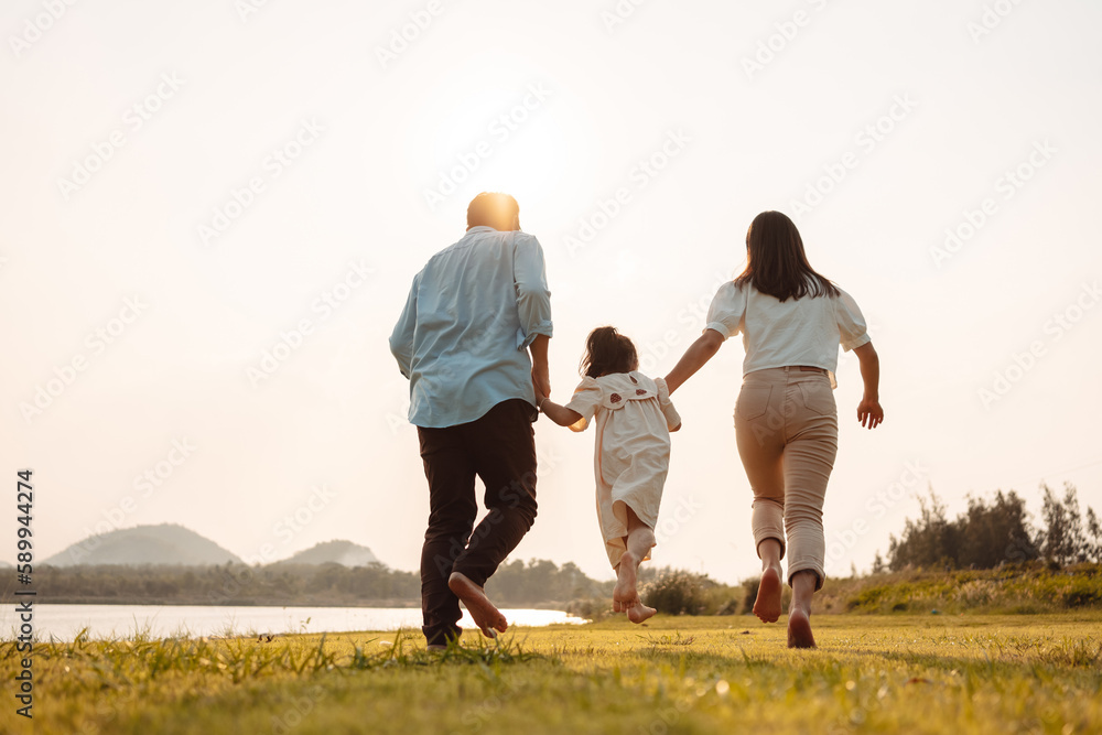 Happy Family enjoying a peaceful walk and running in a scenic field with a serene lake in the background. Happy Family enjoying a peaceful walk and running in a scenic field with a serene lake in the background.