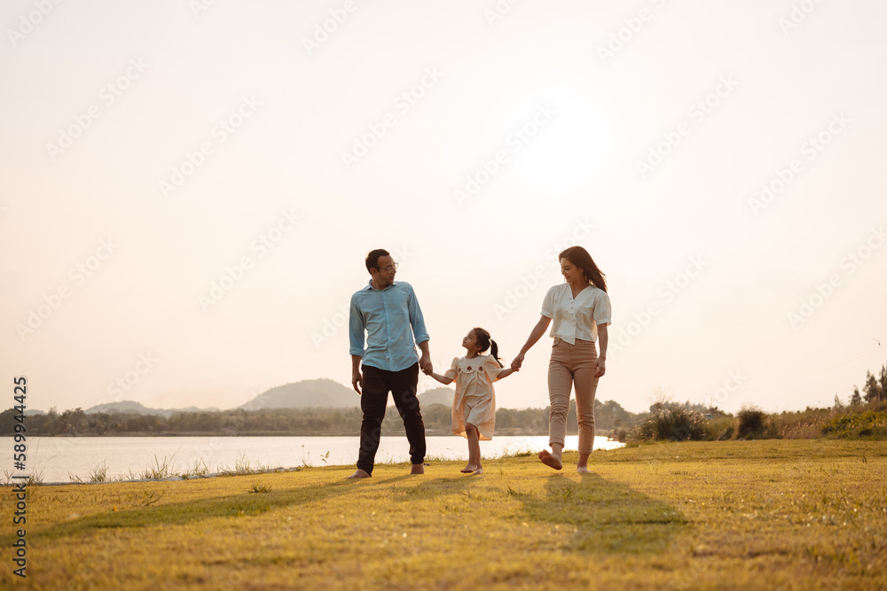 Happy Family enjoying a peaceful walk and running in a scenic field with a serene lake in the background.