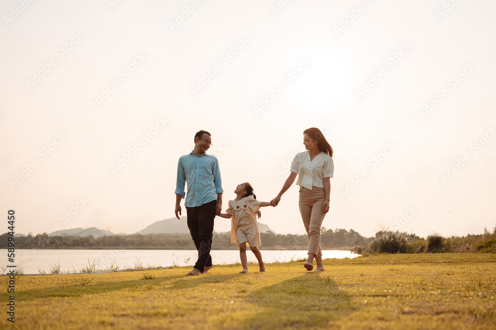 Happy Family enjoying a peaceful walk and running in a scenic field with a serene lake in the background.