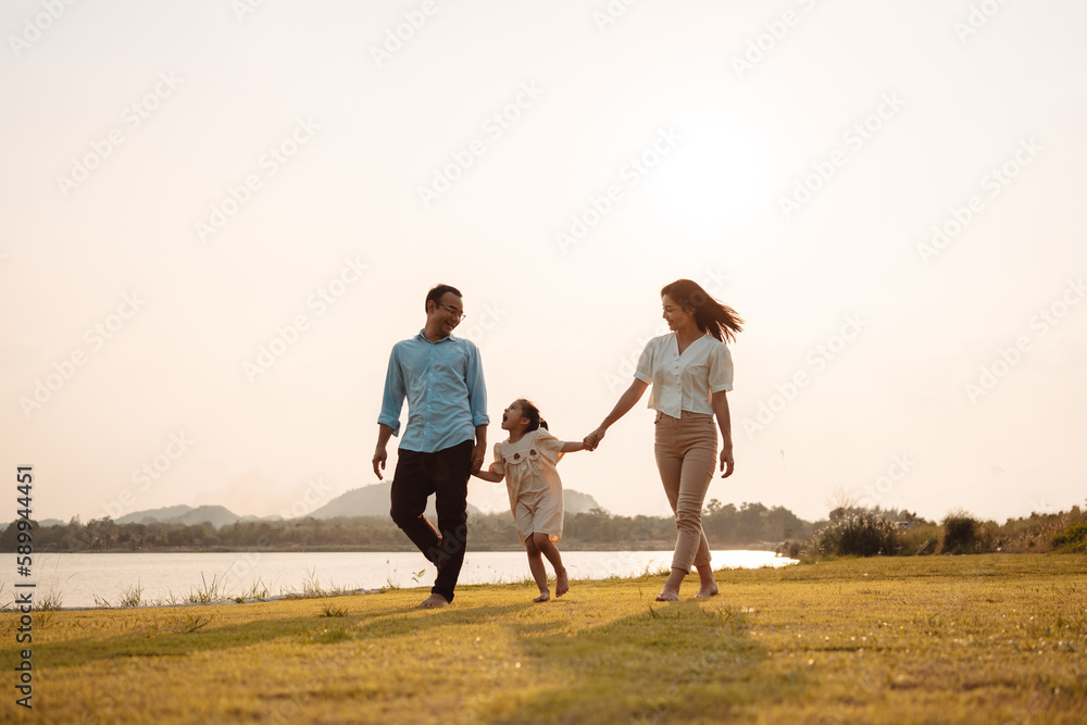 Happy Family enjoying a peaceful walk and running in a scenic field with a serene lake in the background.