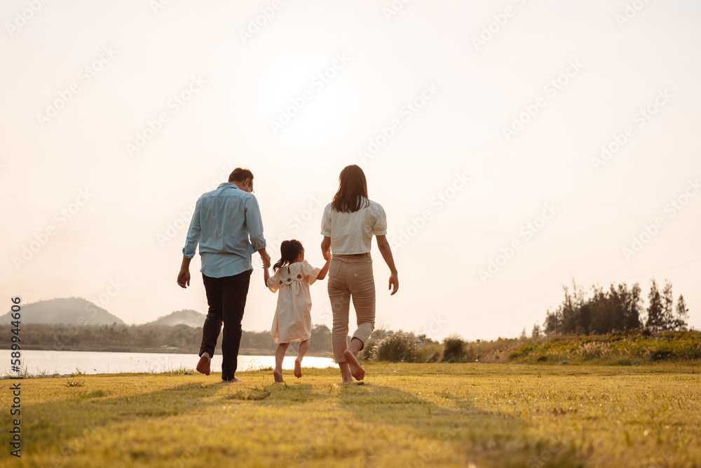 Happy Family enjoying a peaceful walk and running in a scenic field with a serene lake in the background. Happy Family enjoying a peaceful walk and running in a scenic field with a serene lake in the background.