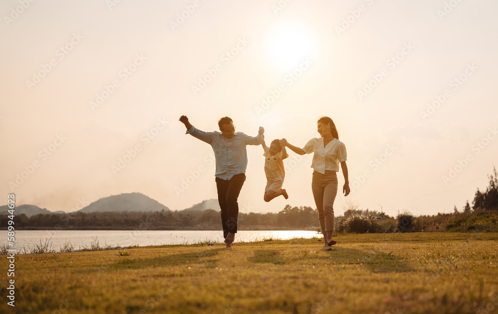 Fototapeta premium Happy Family enjoying a peaceful walk and running in a scenic field with a serene lake in the background.