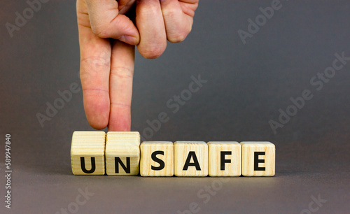 Safe or unsafe symbol. Concept word Safe Unsafe on wooden cubes. Businessman hand. Beautiful grey table grey background. Business safe or unsafe concept. Copy space.