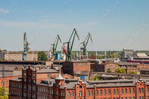 Port with ships, ferries, cranes. ?ranes for loading, unloading various cargoes and containers. Port of Gdansk. Barges in docks of the Baltic sea. Factories in the background.