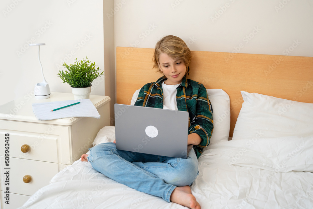 Smart caucasian middle School child boy using laptop. Child typing on the keyboard. Play video game.Online tutor teaching digital class, web lesson on computer at home. Virtual education. E-education Smart caucasian middle School child boy using laptop. Child typing on the keyboard. Play video game.Online tutor teaching digital class, web lesson on computer at home. Virtual education. E-education