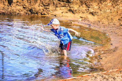 Fototapeta Naklejka Na Ścianę i Meble -  Boy splashes water in the river, Gorokhovets