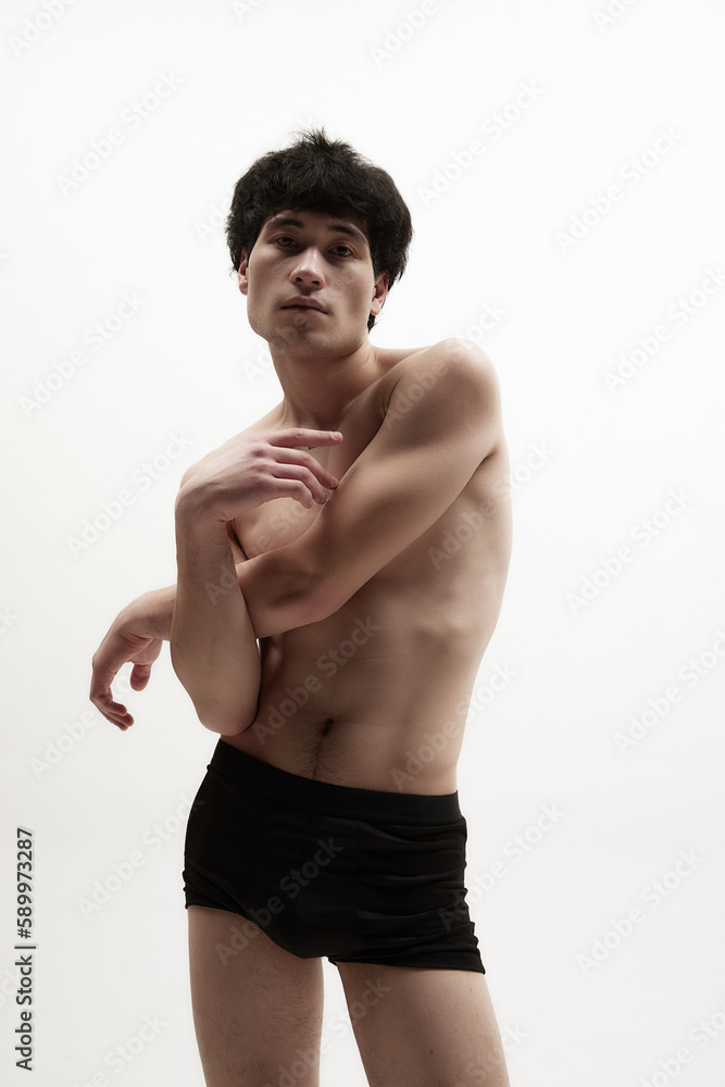Portrait of young asian man posing in black underwear against white studio background. Relief, fit, strong male body. Concept of male body aesthetics, style, fashion, health, men's beauty Portrait of young asian man posing in black underwear against white studio background. Relief, fit, strong male body. Concept of male body aesthetics, style, fashion, health, men's beauty