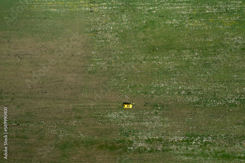 Top view of a yellow retro car on the summer green meadow field with white flowers distant plan