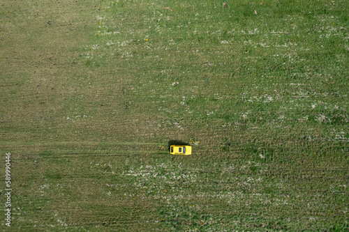 Top view of a yellow retro car on the summer green meadow field with white flowers distant plan