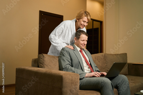 Man in business suit works on laptop on soft sofa