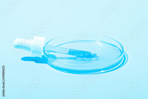 A cosmetic pipette lies in a Petri dish with a blue liquid. Or a blue liquid with glitter. Laboratory research of cosmetics, gel, medicine. Chemistry