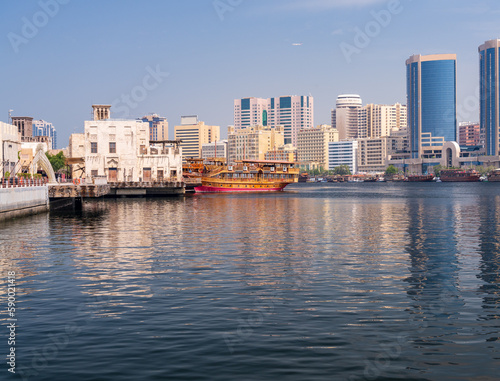 View along the Creek towards Deira with large dhow tour boats docked by the Al Seef boardwalk in Dubai, UAE © steheap