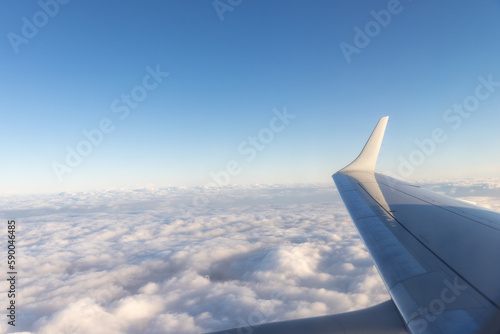 view of jet plane wing on the background of thick clouds and blue sky