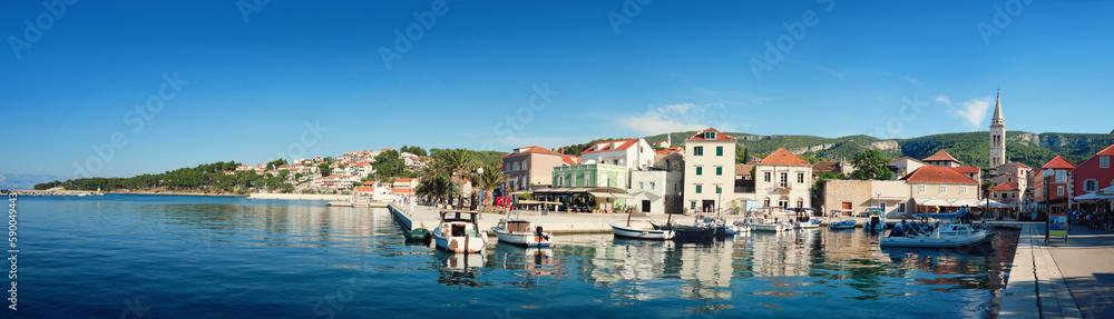 Panoramic travel banner, village on island Hvar, Croatia, Dalmatia, with historical buildings, church and promenade reflected in calm sea water