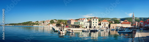 Panoramic travel banner, village on island Hvar, Croatia, Dalmatia, with historical buildings, church and promenade reflected in calm sea water