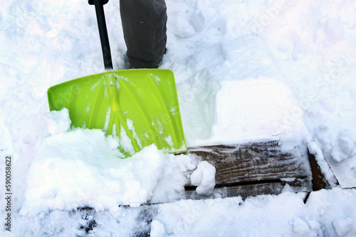 Man is shoveling and removing snow in front of his house in the suburb after a snowstorm