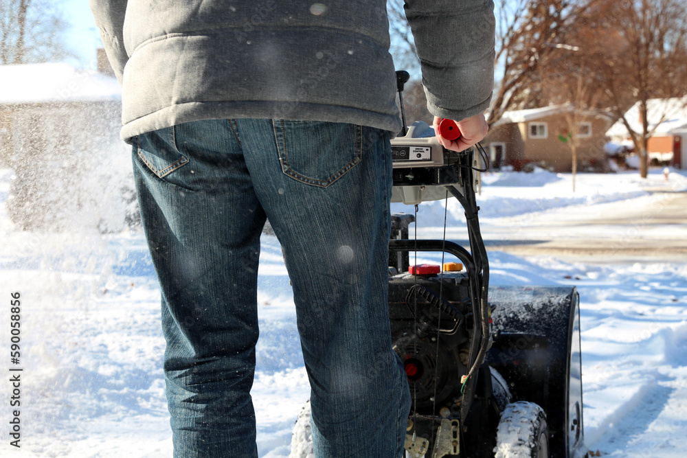 A man is cleaing snow from sidewalks with a snowblower after a snowstorm. A man is cleaing snow from sidewalks with a snowblower after a snowstorm.