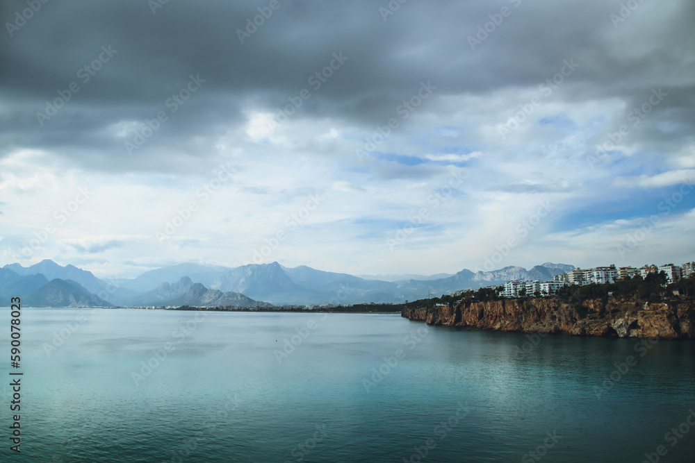 Obraz premium Mediterranean Sea with mountains and apartment buildings in the distance seen from Antalya coast, Turkey
