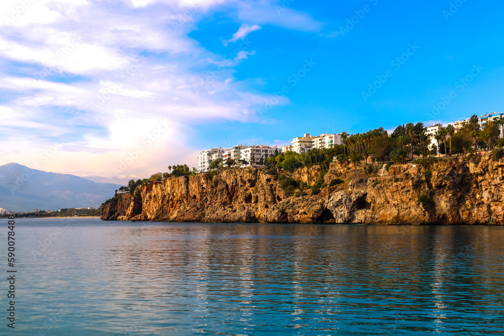 Coast of Antalya harbour with cliff and stones in the sea during a sunny day