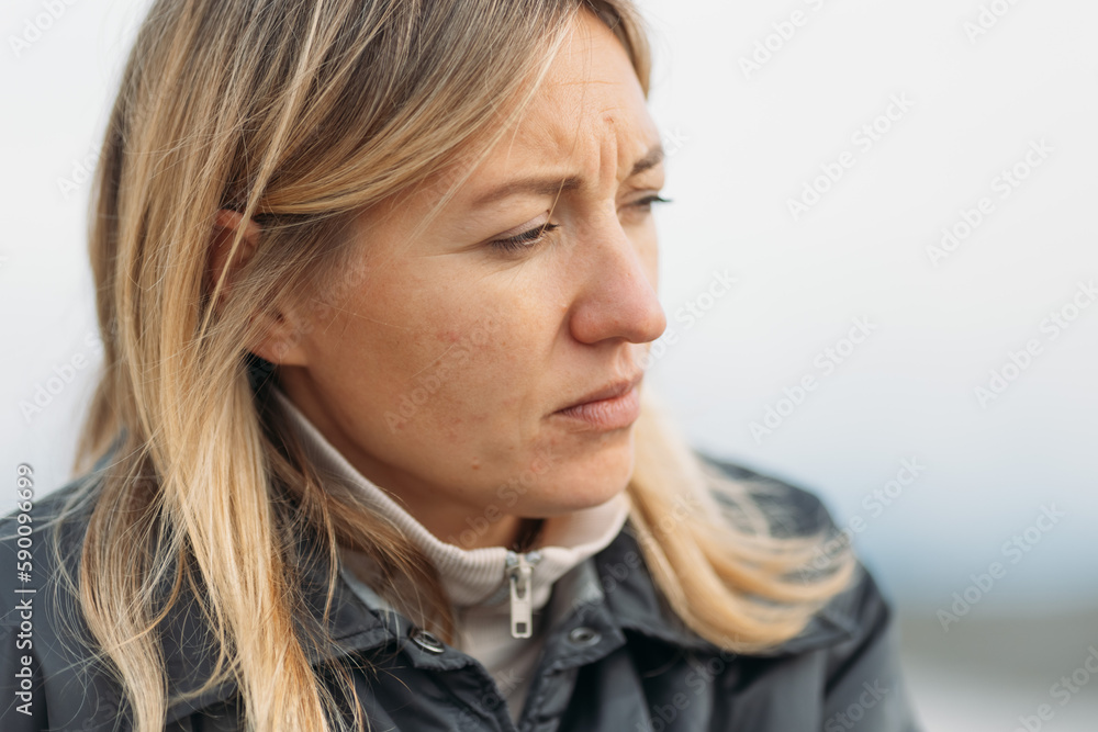 © Ann - Close up of woman face with frowning expression and wrinkles, woman is troubled and upset, woman bent brows