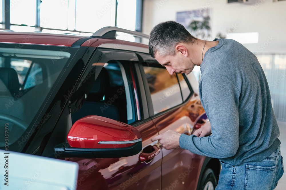 A man examines a car in the cabin for defects. Car rent. Buying a car A man examines a car in the cabin for defects. Car rent. Buying a car