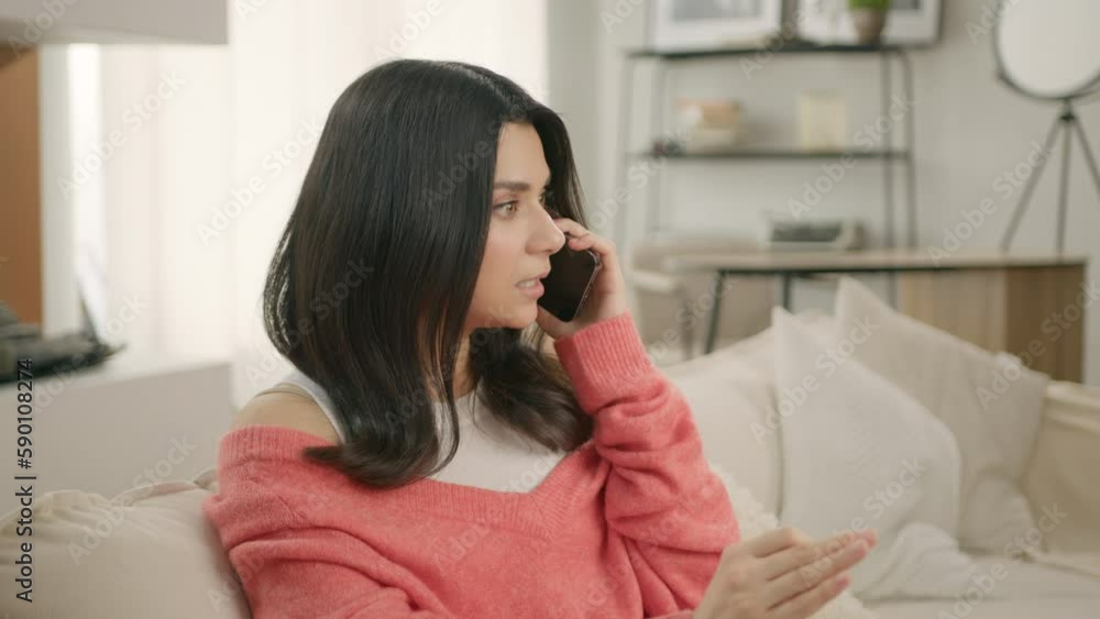 Contented casual brunette woman talking on phone with friends or family rejoicing smiling with white teeth indoors at modern home. Girl makes online order on smartphone inside, concerned customer 4K Contented casual brunette woman talking on phone with friends or family rejoicing smiling with white teeth indoors at modern home. Girl makes online order on smartphone inside, concerned customer 4K