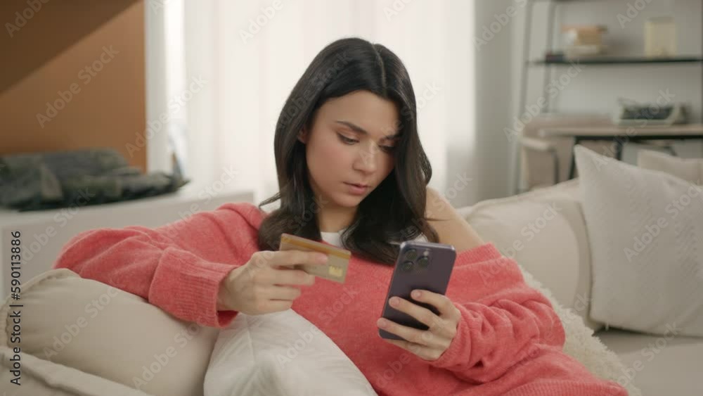Calm concentrated lady with credit card using smartphone to pay online, buy consumer goods, order services on ecommerce websites from home. Focused young brunette woman making ebank safe transaction Calm concentrated lady with credit card using smartphone to pay online, buy consumer goods, order services on ecommerce websites from home. Focused young brunette woman making ebank safe transaction