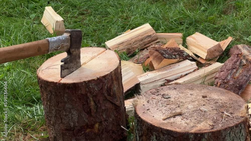 A man chopping wood with an axe in the village on a stump. A man chopping wood with an axe in the village on a stump.