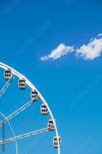 Part of ferris wheel against a blue sky background. Ferris wheel with cabins in a minimalist style. Straight view of ferris wheel for background and abstract compositions.