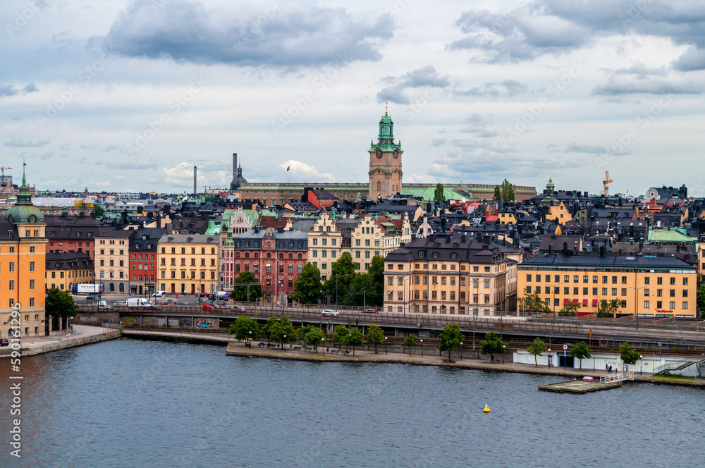 Stockholm, Sweden - City skyline with tower, old houses on waterfront and main road. Waterfront and harbor on the sea channel.