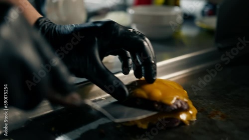 professional kitchen in hotel restaurant chef puts smash burger patty with cheese on burger buns prepares dish serving