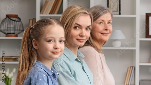 Cute little girl posing indoors with young mother and senior grandmother, side profile view, closeup portrait. Lifespan, next generation, offspring and heredity. For Mothers Day.