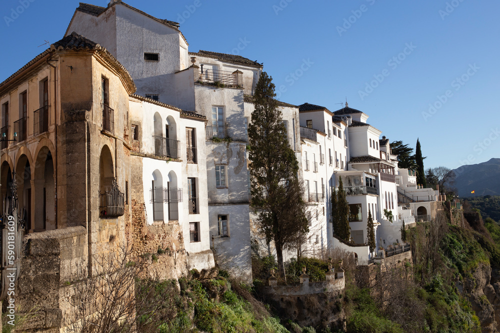 Landscape of old white buildings on the rocks of the gorge on a sunny day. Landmark of the city of Ronda, Malaga, Andalusia, Spain.