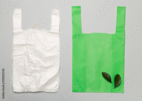 Plastic and biodegradable bag on color background, top view