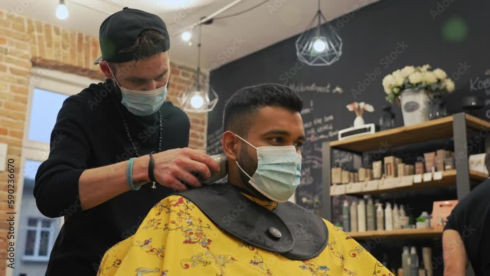 Hairdresser carefully using a trimmer to neaten up the haircut of his