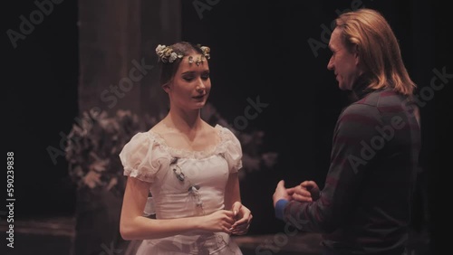 Choreographer teacher mentor trainer of classical dance and ballet teaches posture help  girl ballerina on stage after the performance.