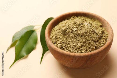 Henna powder and green leaves on beige background, closeup. Natural hair coloring © New Africa