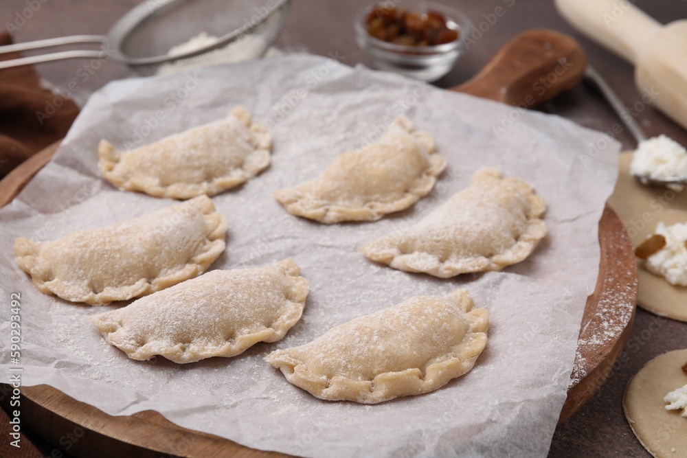 Process of making dumplings (varenyky) with cottage cheese. Raw dough and ingredients on brown table, closeup