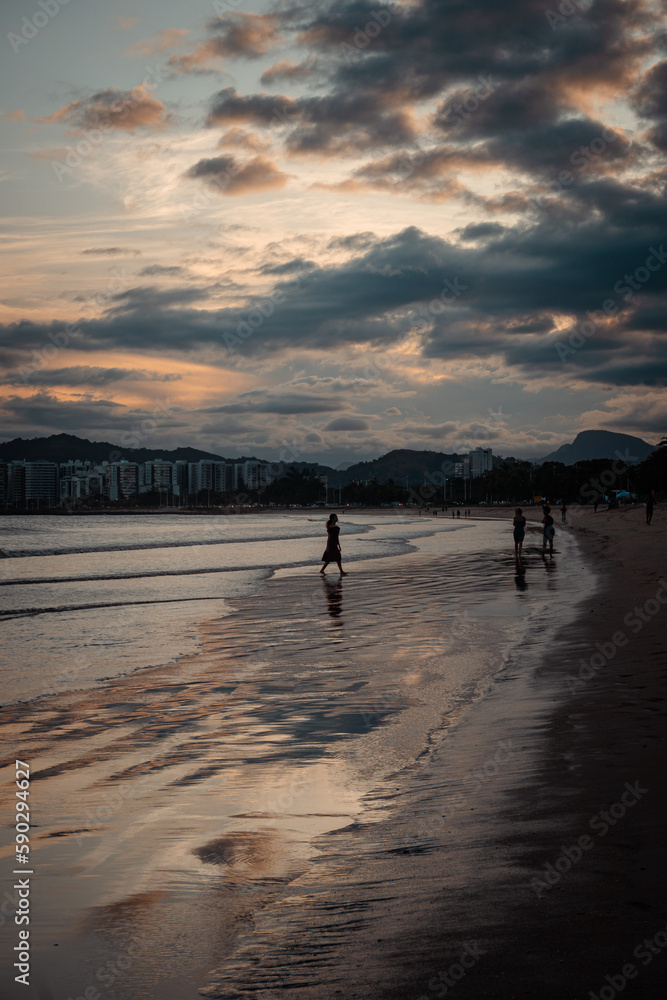 Sombra de mulher e pessoas na praia ao pôr-do-sol com nuvens no céu Sombra de mulher e pessoas na praia ao pôr-do-sol com nuvens no céu