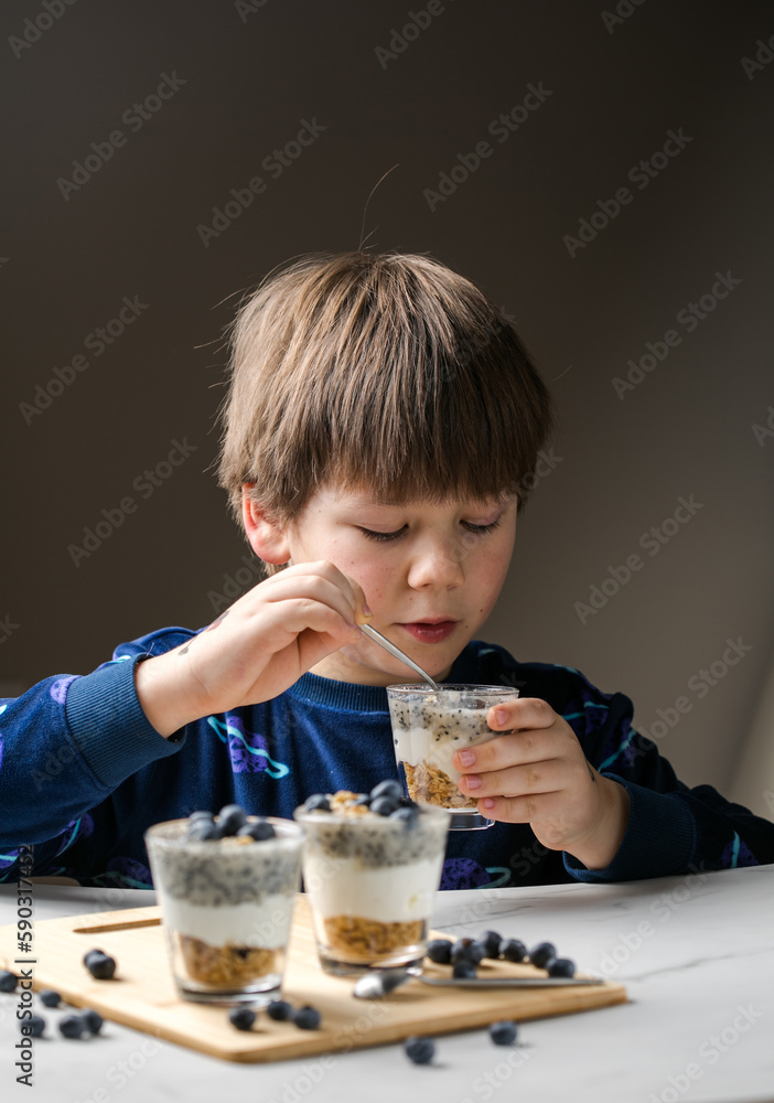 Kid eating parfait. Child eats organic food. Healthy vegetables with vitamins. Proper kids nutrition concept. Kid eating parfait. Child eats organic food. Healthy vegetables with vitamins. Proper kids nutrition concept.