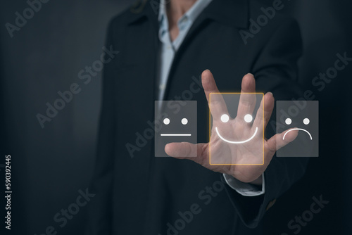 Close up Man hand choosing happy smile face icon on virtual screen to feedback rating and positive customer review experience of product and service concept, Customer servisce satisfaction survey. photo