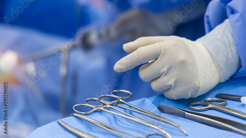 A surgeon or Doctor with nurse team in blue uniform did surgery inside operating room in hospital.Surgeon picking up surgical clamps and medical equipment with light.Emergency surgery was done.